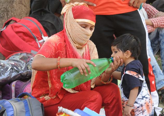 A woman helps her child to drink water from a bottle in the scorching heat at Chandigarh College of Engineering and Technology in Sector 26, Chandigarh, on Tuesday.(Keshav Singh/HT)