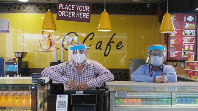 Vendors wear protective masks and face shields while working at a cafe in the Indira Gandhi International Airport. Flights to and from West Bengal will resume on May 28 and those operating from Andhra Pradesh will commence from May 26. (T. Narayan / Bloomberg)