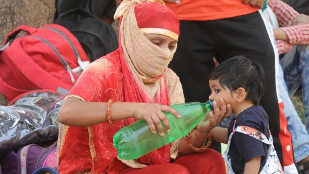A mother quenching her child’s thirst as they wait under the scorching sun to board the special Shramik train in Chandigarh on Tuesday. (Keshav Singh/HT)
