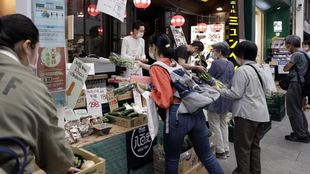 Customers wearing protective masks shop for vegetables at a stall in front of a restaurant in the Kichijoji area of Tokyo on May 26. The state of emergency had enabled local governments to instruct businesses to close or operate for shortened hours, and to ask residents to stay at home. Most fell in line with instructions. (Kiyoshi Ota / Bloomberg) Customers wearing protective masks shop for vegetables at a stall in front of a restaurant in the Kichijoji area of Tokyo on May 26. The state of emergency had enabled local governments to instruct businesses to close or operate for shortened hours, and to ask residents to stay at home. Most fell in line with instructions. (Kiyoshi Ota / Bloomberg)