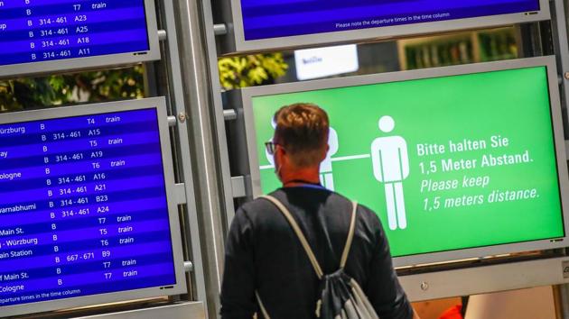 A social distancing sign sits beside flight departure information screens at Frankfurt Airport.(Bloomberg)