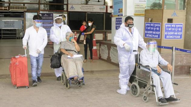 Airport staff in PPE coveralls help wheelchair using travellers exit the arrivals area after landing at Jaiprakash Narayan International Airport in Patna on May 25. (Santosh Kumar / HT Photo)