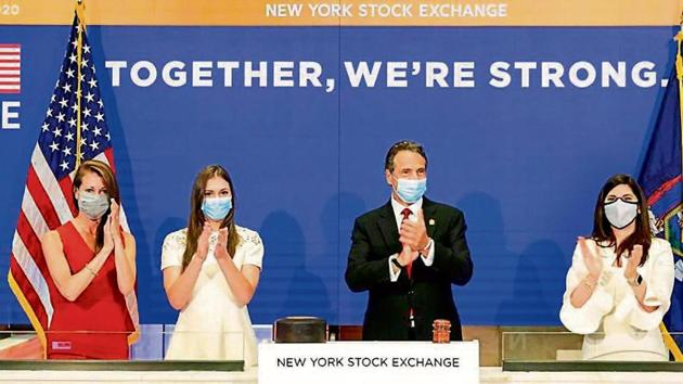 New York State Governor Andrew Cuomo (centre) applauds as he rings the opening bell of the New York Stock Exchange with NYSE president Stacey Cunningham (right) on Tuesday.(AP)