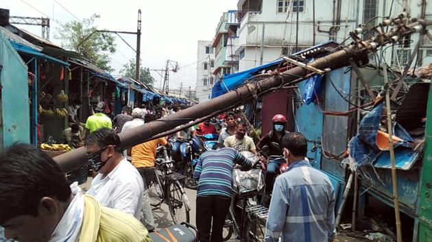 Commuters face hurdles while crossing a road due to an electric pole which was uprooted by Cyclone Amphan, at Hooghly in Kolkata on Tuesday. (ANI Photo) Commuters face hurdles while crossing a road due to an electric pole which was uprooted by Cyclone Amphan, at Hooghly in Kolkata on Tuesday. (ANI Photo)