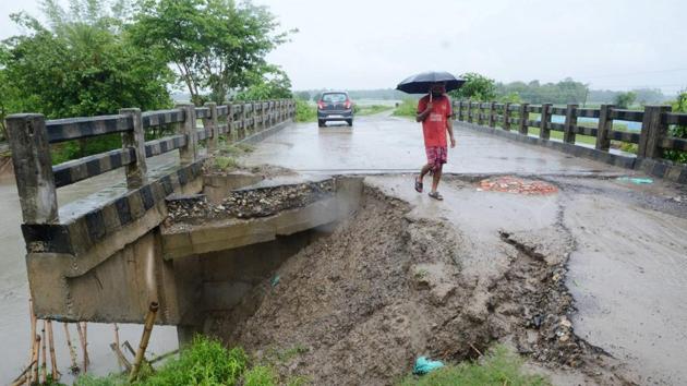 A man stands walks over a bridge damaged due to incessant rainfall at Dhamdhama in Nalbari district on May 26. (PTI)