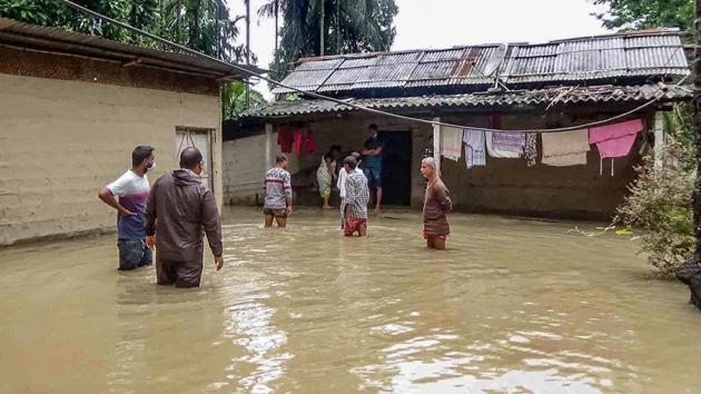 People outside their house in a flood-affected village in Nalbari district of Assam on May 26. A total of 1,007 hectares of crop area has been submerged due to flooding and around 16,500 domestic animals and poultry affected, ASDMA said. (PTI)