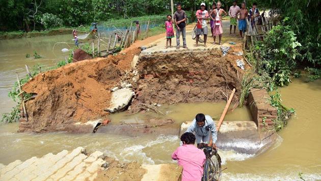 Villagers try to cross a road where the portion was washed away by flood water at Sukunia in Kamrup on May 26. Parts of Assam and neighbouring Meghalaya have been receiving extremely heavy rains since May 20 after super cyclone Amphan weakened. (ANI)