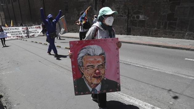 A protester carries an image of Ecuador’s President Lenin Moreno depicted as a clown with coronavirus-like spikes around his face. Moreno last week announced public spending cuts including the closure of state companies and embassies around the world, but trade unions on May 25, said workers were paid a disproportionate price compared to Ecuador’s elite. (Dolores Ochoa / AP) A protester carries an image of Ecuador’s President Lenin Moreno depicted as a clown with coronavirus-like spikes around his face. Moreno last week announced public spending cuts including the closure of state companies and embassies around the world, but trade unions on May 25, said workers were paid a disproportionate price compared to Ecuador’s elite. (Dolores Ochoa / AP)