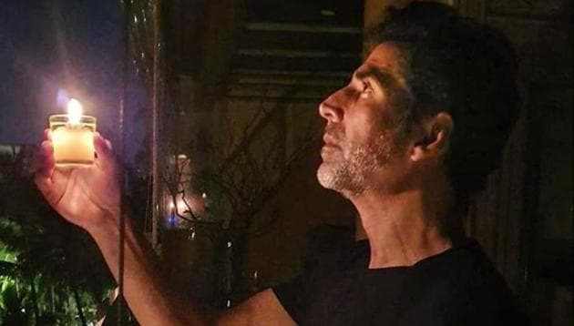 Bollywood actor Akshay Kumar holds a candle in response to Prime Minister Narendra Modi’s call to light lamps to express solidarity with the country’s fight against the novel coronavirus.(PTI)