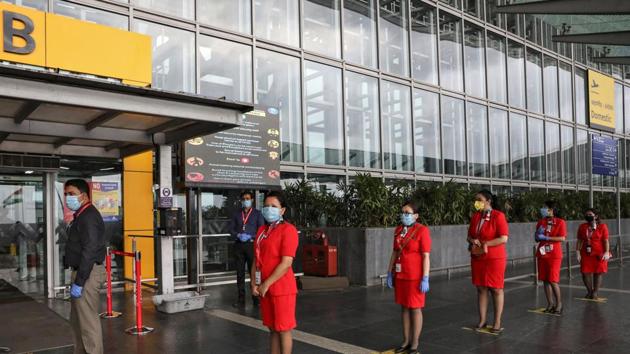 AirAsia staff members stand on social distancing markings, as they wait to enter Netaji Subhas Chandra Bose International Airport in Kolkata, on Wednesday.(Reuters Photo)