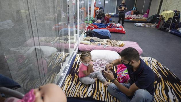 Juan David, who lost his job in Brazil and is trying to return home to Colombia, prepares chocolate milk for his daughter Luciana at the Guarulhos International Airport on May 27, 2020. Most people have made the check-in area home, a few sleep on mattresses and others atop cloth sheets or flattened cardboard boxes. Some have stretched out on the bare floor. (Andre Pener / AP) Juan David, who lost his job in Brazil and is trying to return home to Colombia, prepares chocolate milk for his daughter Luciana at the Guarulhos International Airport on May 27, 2020. Most people have made the check-in area home, a few sleep on mattresses and others atop cloth sheets or flattened cardboard boxes. Some have stretched out on the bare floor. (Andre Pener / AP)