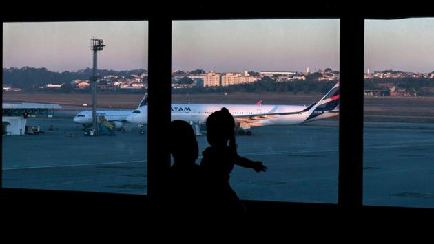 A Colombian citizen and a girl look at planes sitting on the tarmac at Guarulhos International Airport, near Sao Paulo, Brazil on May 26.For several weeks now life has been an interminable layover for the Colombian nationals stuck in Latin America’s coronavirus hot spot. (Miguel Schincariol / AFP) A Colombian citizen and a girl look at planes sitting on the tarmac at Guarulhos International Airport, near Sao Paulo, Brazil on May 26.For several weeks now life has been an interminable layover for the Colombian nationals stuck in Latin America’s coronavirus hot spot. (Miguel Schincariol / AFP)