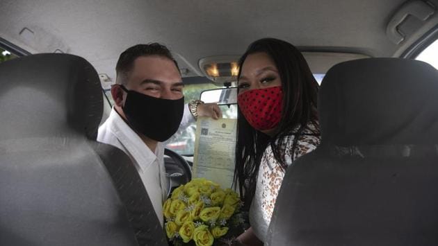 Ayrton (L) and Natasha (R) wearing masks, pose for a photo after their drive-thru wedding at the registry office in Santa Cruz, a neighbourhood on the western outskirts of Rio de Janeiro, Brazil. The drive-thru marriage perhaps wasn’t the most romantic thing people had planned for themselves, but it is a viable option in these times. (AP)