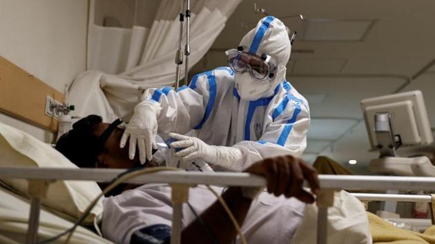 A medical worker wearing personal protective equipment takes care of a patient suffering from the coronavirus disease, at a hospital in Delhi on Thursday.(Reuters Photo)