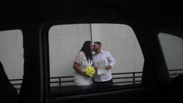 Ayrton and Natasha kiss after their drive-thru wedding. “We saw the need to create a way to hold a safe celebration that was fast and within regulations,” Alessandra Lapoente, the notary who officiates such weddings told AP. “We made the ceremony brief, but with all the requirements, and everyone leaves happy,” Lapoente added. (Silvia Izquierdo / AP)