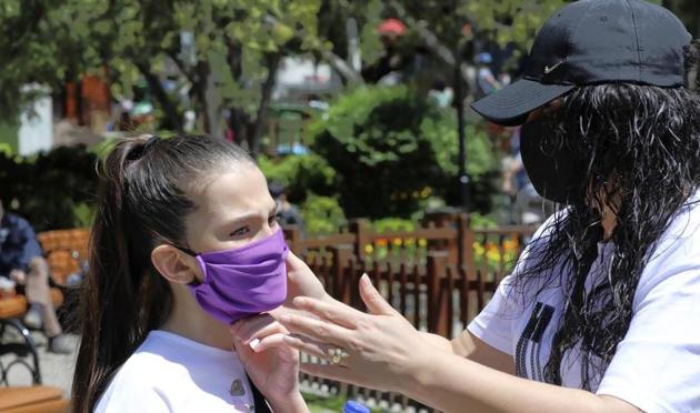 A mother wearing a face mask for protection against the coronavirus, adjusts her daughter's mask in Kugulu public garden, in Ankara, Turkey, Wednesday, May 13, 2020.(AP)