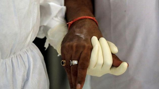 A medical worker wearing personal protective equipment (PPE) helps a patient suffering from the coronavirus disease (COVID-19), inside a high-dependency unit ward at the Max Smart Super Speciality Hospital in New Delhi.(REUTERS)