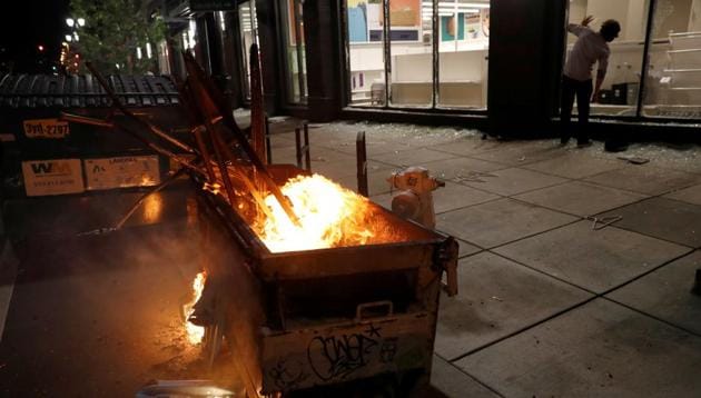 A burning trash container is seen outside a ransacked Target during a protest against the death of African-American man George Floyd under Minneapolis police custody, in Oakland, California, US.(REUTERS) A burning trash container is seen outside a ransacked Target during a protest against the death of African-American man George Floyd under Minneapolis police custody, in Oakland, California, US.(REUTERS)