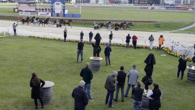 A small group of owners and trainers watch a race at the Addington Raceway. On May 28, the demand for starting places were so great, with 290 horses entering, that the Addington meeting had to be split over two days with nine races on the opening day and twelve on May 29, reported AP. (Mark Baker / AP)
