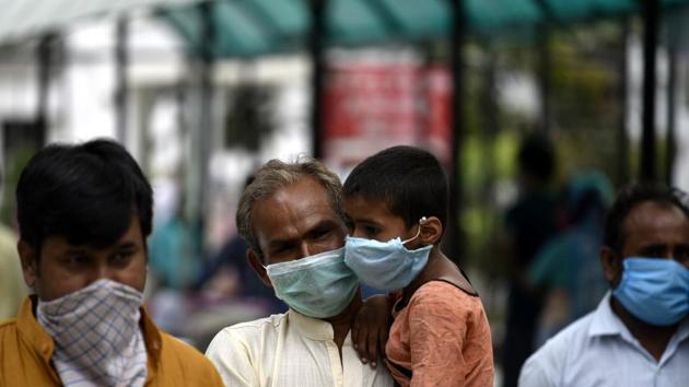 An elderly man carrying a child in his arms during in Lucknow, Uttar Pradesh, May 30 2020.(HT Photo)