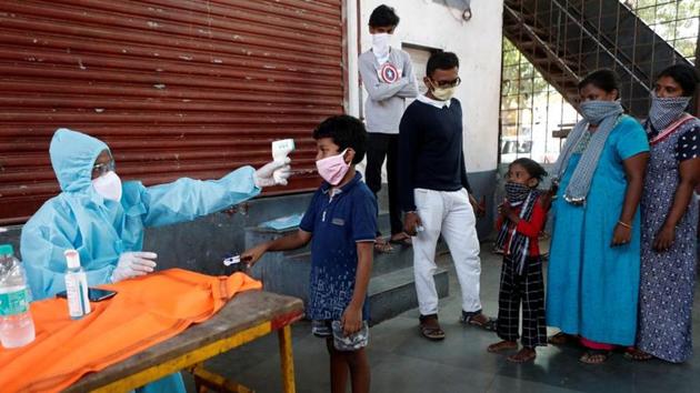 A healthcare worker checks a boy's temperature with an infrared thermometre at a camp in Mumbai’s Dharavi, on Friday.(Reuters Photo)