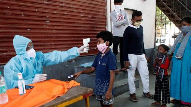 A healthcare worker checks a boy's temperature with an infrared thermometer at a camp in Dharavi, Mumbai.(REUTERS) A healthcare worker checks a boy's temperature with an infrared thermometer at a camp in Dharavi, Mumbai.(REUTERS)