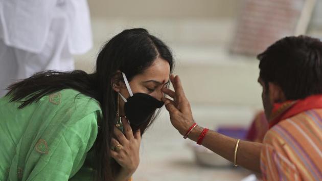 A priest applies vermilion paste on the forehead of a devotee at Kheer Bhawani temple amid the coronavirus pandemic in Jammu, on Saturday.(AP Photo) A priest applies vermilion paste on the forehead of a devotee at Kheer Bhawani temple amid the coronavirus pandemic in Jammu, on Saturday.(AP Photo)
