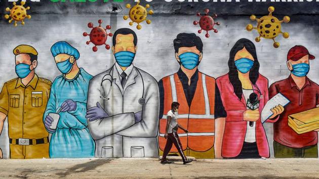A man walks in front of a wall of graffiti paying salute to front line corona warriors in New Delhi on May 31. The Delhi government has attributed the higher number of cases May 28 onwards to the number of Covid-19 samples being processed per day. (Manvender Vashist / PTI)
