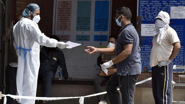 Medical workers in PPE gear guide visitors outside the Covid-19 ward at Lok Nayak Jai Prakash Narayan Hospital (LNJP) in New Delhi on May 30. The Delhi government has set aside 1,870 rooms in 10 plush hotels as paid quarantine facilities for those with mild symptoms such as fever and upper respiratory tract infection. (Sanjeev Verm a/ HT PHOTO)