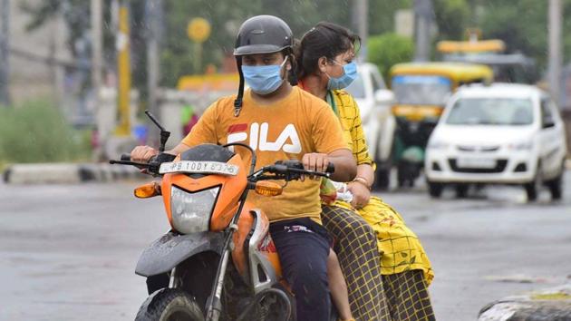 Motorists wearing face masks during their commute amid rain in Ludhiana on Sunday. (Gurpreet Singh/HT) Motorists wearing face masks during their commute amid rain in Ludhiana on Sunday. (Gurpreet Singh/HT)