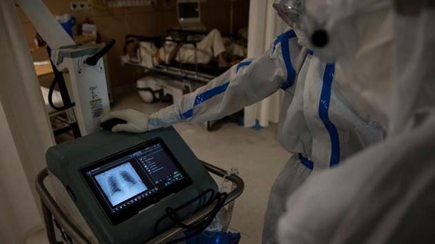 Medical workers look at the chest scan reports of a patient in the ICU. The eerie calm in the hospital is broken only by the sound of machines beeping and patients coughing --most of whom are separated only by white curtains. Staff in heavy protective gear move around softly, speaking in murmurs. (Danish Siddiqui / REUTERS)