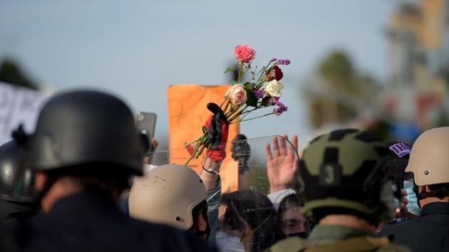 A protester holds up flowers as she confronts a row of police officers during a demonstration over the death of George Floyd in Santa Monica, California, on May 31. (Agustín Paullier / AFP)