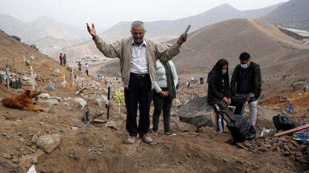 A man prays near relatives during the funeral of their loved one, who died of the coronavirus disease (Covid-19), at the Nueva Esperanza cemetery in Lima, Peru. (REUTERS) A man prays near relatives during the funeral of their loved one, who died of the coronavirus disease (Covid-19), at the Nueva Esperanza cemetery in Lima, Peru. (REUTERS)