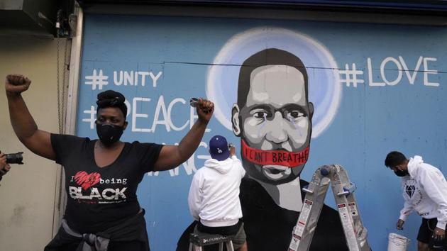 A woman gestures while a mural with an image of George Floyd is painted in the background during a rally against the death in Minneapolis police custody of George Floyd, in Los Angeles, California, US.(REUTERS)