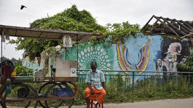 A snack vendor wearing a mask waits for customers near his push cart in Kochi, Kerala. (AP) A snack vendor wearing a mask waits for customers near his push cart in Kochi, Kerala. (AP)
