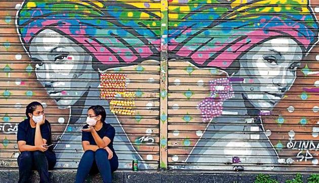 Women talk outside a closed outfit store during quarantine in Sao Paulo, Brazil.