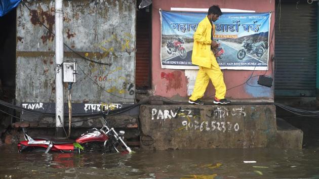 A boy makes his way along a ledge adjacent to a waterlogged street in Mumbai on June 4. Nisarga comes on the heels of Cyclone Amphan, which killed more than 100 people as it ravaged eastern India and Bangladesh last month, flattening villages, destroying farms and leaving millions without electricity. (Shashank Parade / PTI) 