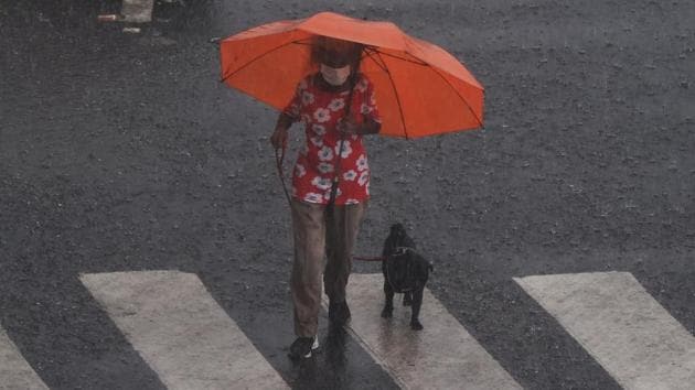 A woman walks her dog in the rain in Mumbai on June 4. An unexpected effect of Cyclone Nisarga and its accompanying rains has been an improvement in Mumbai’s overall air quality index (AQI), which improved to the year’s best at 17 according to the System of Air Quality and Weather Forecasting and Research (SAFAR). (Punit Paranjpe / AFP) 