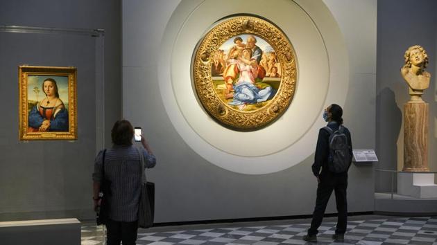 Members of the media admire 15th century painting "Doni Tondo" by Michelangelo Buonarroti, during a press tour of the Uffizi museum on the day off its reopening, in Florence, Wednesday, June 3, 2020. The Uffizi museum reopened to the public after over two months of closure due to coronavirus restrictions.(AP)