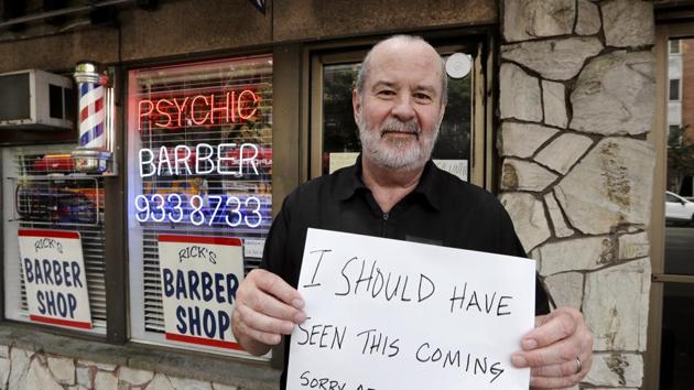 In this photo taken Thursday, June 4, 2020, barber Rick Cook holds the sign he's been playfully displaying in his "Psychic Barber" shop, closed because of the coronavirus outbreak, in Seattle.(AP) In this photo taken Thursday, June 4, 2020, barber Rick Cook holds the sign he's been playfully displaying in his "Psychic Barber" shop, closed because of the coronavirus outbreak, in Seattle.(AP)