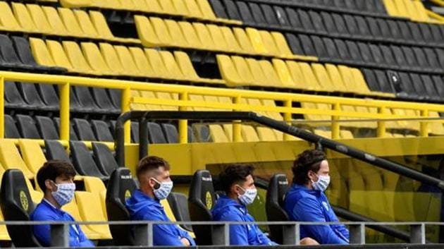 Schalke substitutes wearing protective face masks maintain social distance, as play resumes behind closed doors following the outbreak of the coronavirus disease. (REUTERS)