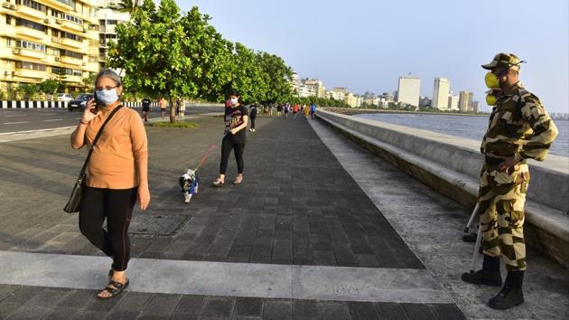 Pedestrians walk along the promenade at Marine Drive, with CISF and Mumbai Police personnel still restricting seating along the parapet, as part of partial lockdown restrictions easing in Mumbai on June 5.  The worst hit state in the country continues to be Maharashtra with a total of 80,229 cases as of last count. (Anshuman Poyrekar / HT Photo) 