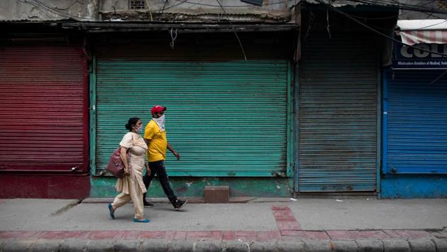 People walk past closed shops along a street in New Delhi on June 5. The lockdown is now largely being enforced in high-risk areas while authorities have partially restored train services and domestic flights and allowed shops and manufacturing to reopen. (Xavier Galiana / AFP) 