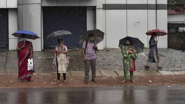 People stand holding umbrellas during monsoon rains in Kochi on June 6. The surge in India’s COVID-19 caseload comes a time when the country is already trying to contain the chain of transmission while allowing social and economic activity to resume. (R S Iyer / AP) 