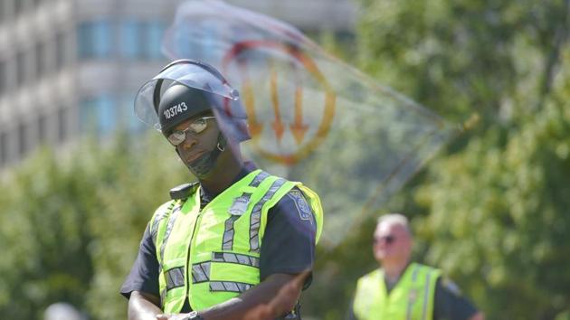 A flag, bearing a leftist symbol associated with Antifa, is reflected behind a Boston Police officer during the Straight Pride Parade rally in Boston, Massachusetts, US.(REUTERS) A flag, bearing a leftist symbol associated with Antifa, is reflected behind a Boston Police officer during the Straight Pride Parade rally in Boston, Massachusetts, US.(REUTERS)