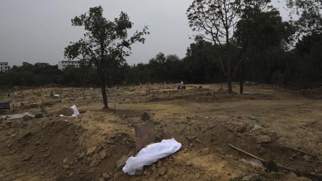 A personal protective suit lies on a grave of a of a person at the designated burial spot for COVID-19 patients at a cemetery in New Delhi on June 5. India has lost 6,672 lives to the disease as of today evening and ranks twelfth globally in the number of casualties resulting from the pandemic. (AP) 
