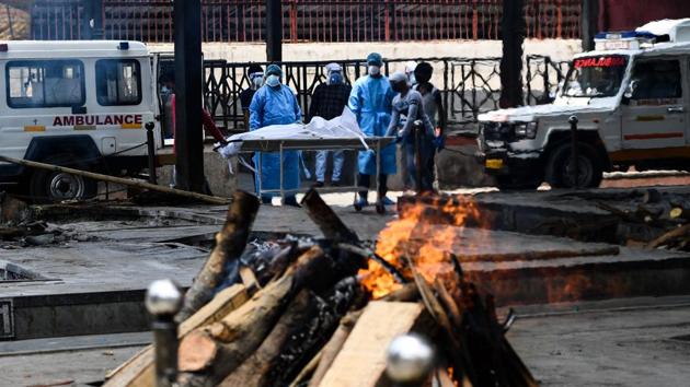 Relatives and workers wearing Personal Protective Equipment (PPE) watch as the body of a person who died of COVID-19 is cremated in a pyre, at the Nigambodh Ghat cremation ground in New Delhi. Traditional funeral pyres have been drafted in to cremate bodies of coronavirus victims in Delhi as furnaces struggle to keep up with the mounting death toll. (Sajjad Hussain / AFP)