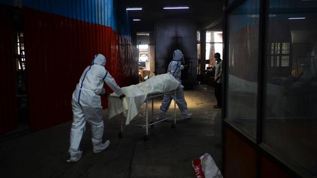 Workers move the body of person who died of COVID-19, before cremation at Nigambodh Ghat. Suman Kumar Gupta of the crematorium management committee said families arriving for a funeral had to queue to pass through a “sanitation tunnel” at the entrance and then wait hours for the ceremony, prompting anxiety about the risk of infection, AFP reported. (Sajjad Hussain / AFP)