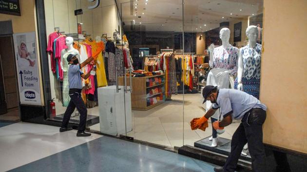 Workers clean the entrance gate of a shop in mall in Noida on Saturday ahead of its re-opening on June 8.(PTI Photo)