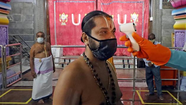 A priest wearing undergoes thermal screening before entering a temple ahead of its reopening for devotees, in Bengaluru on June 6. As per central government guidelines, religious places, malls, restaurants and hotels will reopen on June 8 after a gap of more than 70 days since the lockdown was imposed to curb the spread of coronavirus. (PTI)